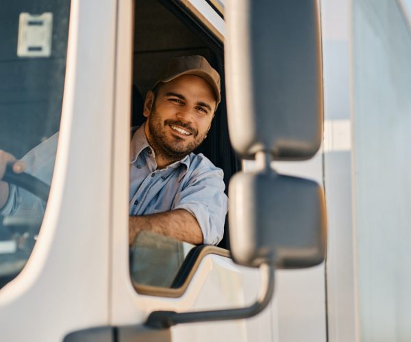 Happy truck driver looking through side window while driving his truck.