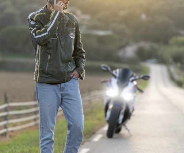 Young man with motorcycle breakdown on the road talking on the phone